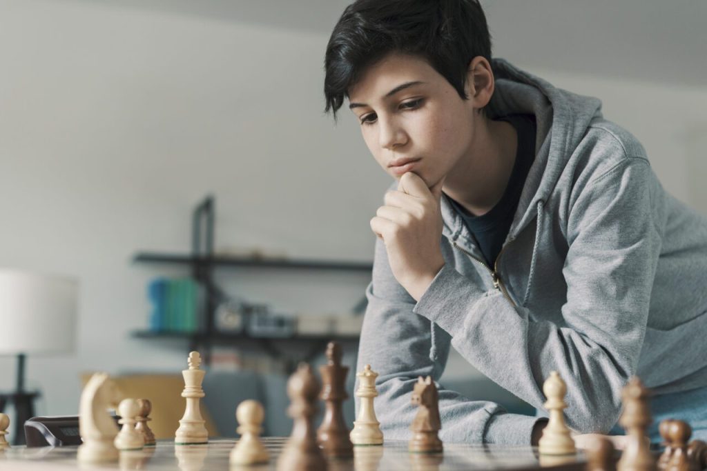 Smart boy playing chess and staring at the chessboard e1698161801842.jpg